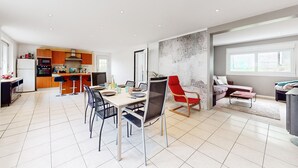 A modern kitchen with wooden cabinets and a dining area with a table and chairs. - 3 bedroom stunning home in Lanvaudan (Lanvaudan)