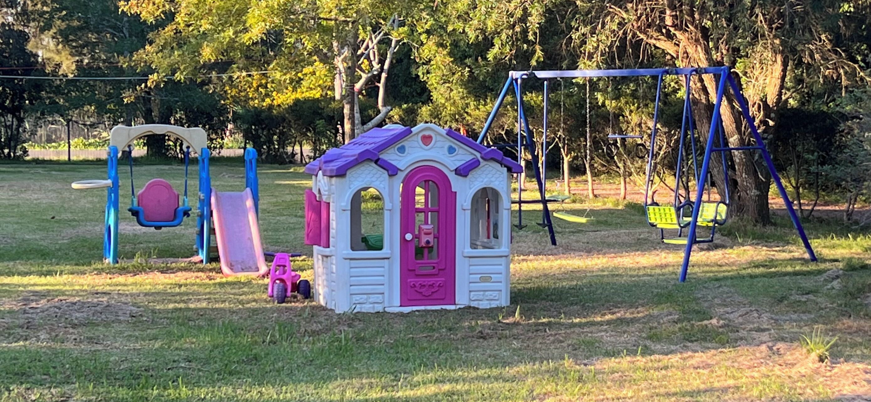 A children's play area with a small house, swings, and a slide.