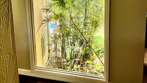A room with a large window overlooking a lush garden.