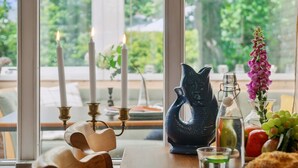 A table with candles, a pitcher, a vase with flowers, and a glass of water.
