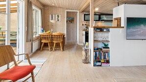 A wooden interior with a dining area, bookshelves, and a television.