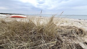 A beach with sand dunes and a red boat in the background.