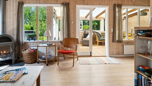 A cozy cabin interior with a fireplace, wooden floors, a dining area, and a view of the outdoors.
