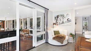 Un salon moderne avec un canapé blanc, un banc en bois et un coin repas doté d’une table en bois.