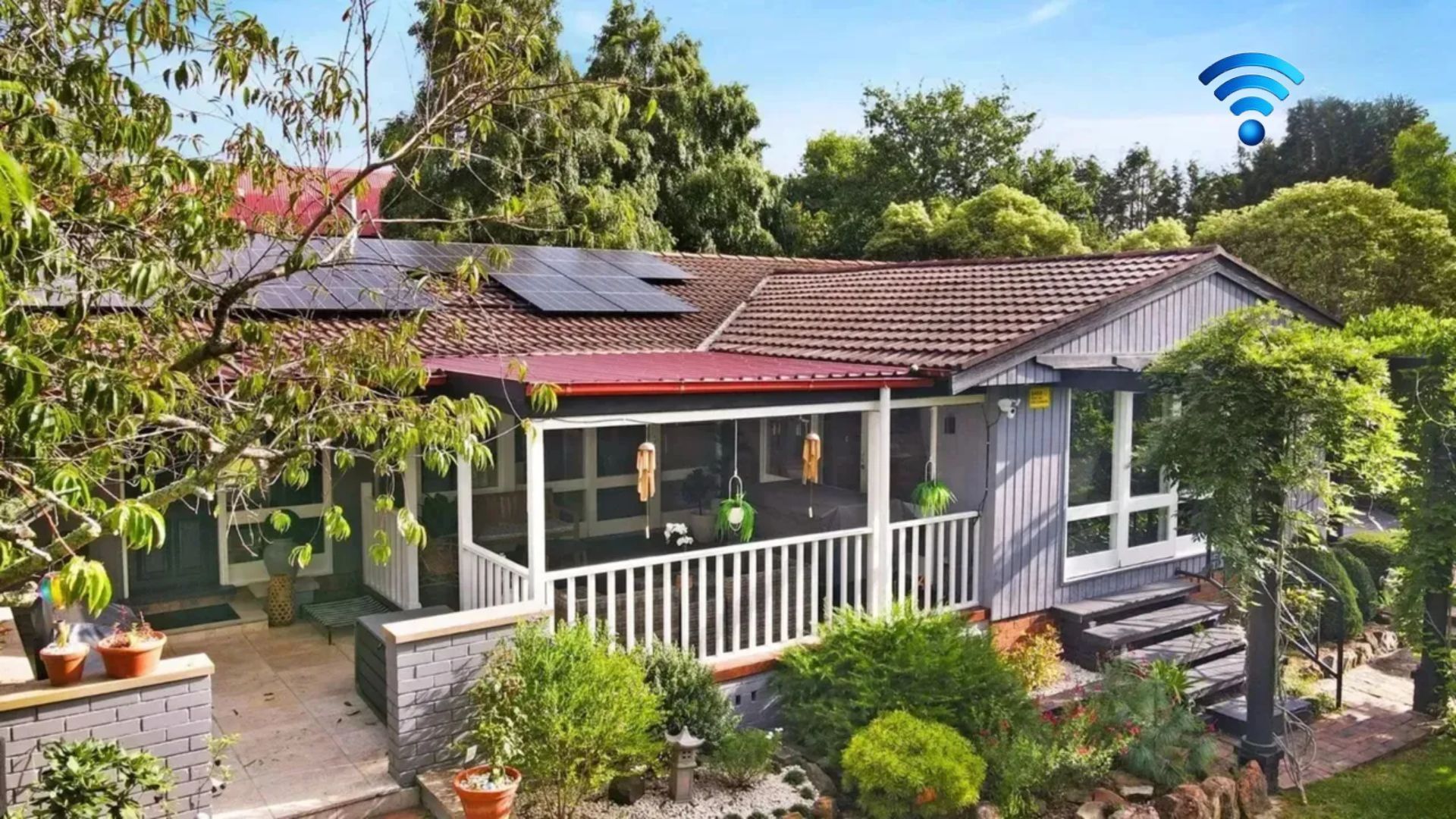 A house with a red-tiled roof, a covered porch, and solar panels.