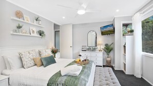 Une chambre moderne avec un lit, une table de chevet, une commode et une grande fenêtre donnant sur un beau paysage.
