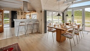 Una cocina moderna con una isla grande, taburetes de bar y un comedor con mesa y sillas de madera.