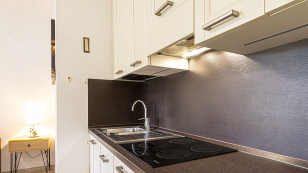 A modern kitchen with a black stovetop, stainless steel sink, and white cabinets. - Gardenia Apartment, centrally located, perfect for those who want to forget the car, with outdoor sp (Marina di Campo)