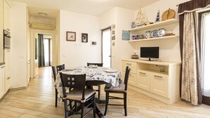 A dining area with a table set for four, surrounded by chairs. There is a television on a stand to the right. - Gardenia Apartment, centrally located, perfect for those who want to forget the car, with outdoor sp (Marina di Campo)