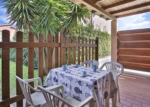 A covered patio with a table set for two, surrounded by wooden chairs, under a wooden pergola. - Eden apartment, in a residential area in Marina di Campo, with air conditioning, private parking spa (Marina di Campo)