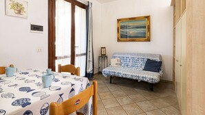Une pièce chaleureuse comprenant une table à manger, des chaises, un canapé, un tableau et une armoire en bois.
