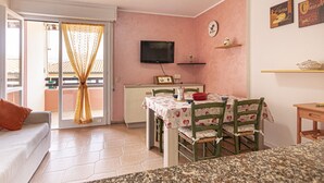 Una sala de estar acogedora con sofá, mesa de comedor con sillas, televisor y zona de cocina con microondas y cafetera.
