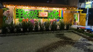 Une auberge de jeunesse à la façade colorée, avec une enseigne indiquant « Hostel Casa da Ana » et une entrée fermée par un portail.
