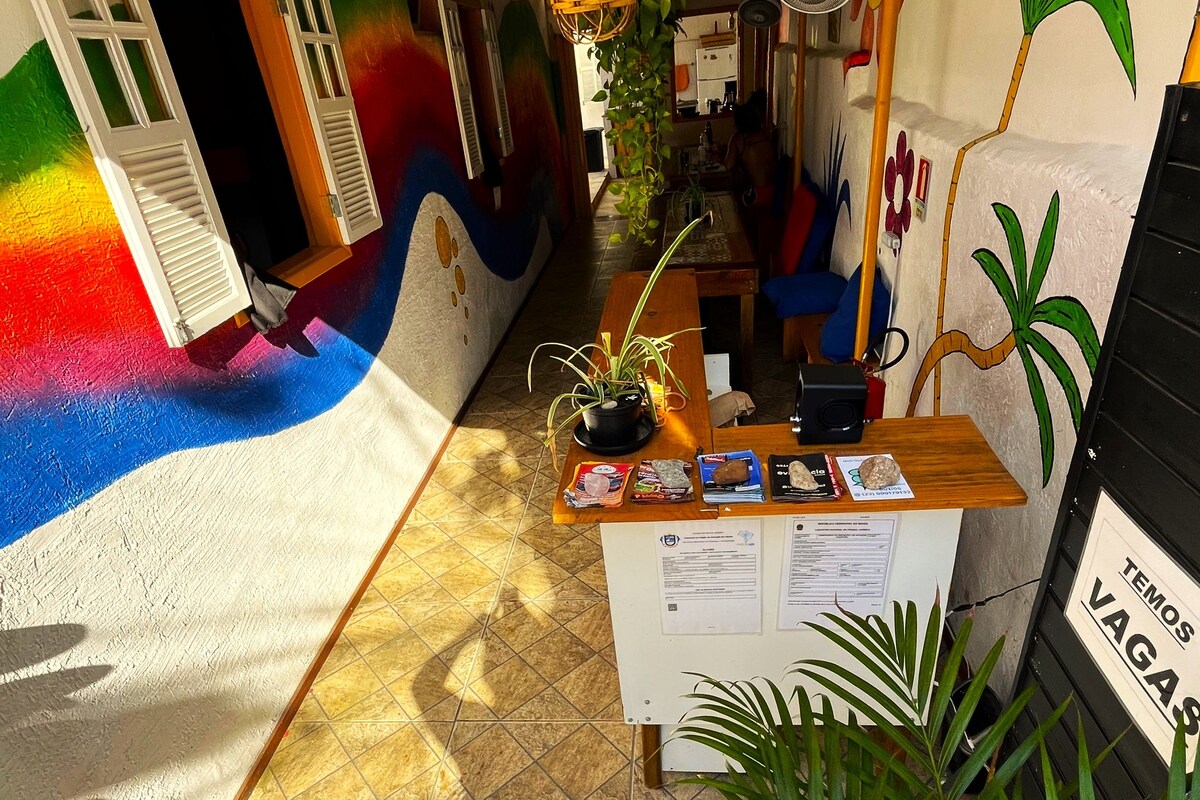 A narrow hallway with a tiled floor, a reception desk with a sign, and a wall with a mural.