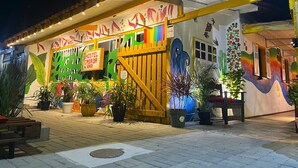 Une auberge de jeunesse aux murs ornés de peintures murales colorées, avec une enseigne indiquant « Auberge Casa da Ana » et des plantes en pot.
