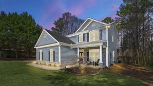 A two-story house with a stone foundation, a large front porch, and a well-maintained lawn. - Luxury Home - ATL - No Cleaning Fee! (Austell)
