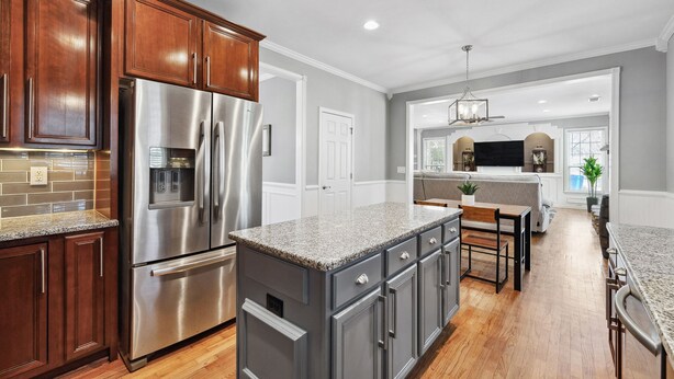 A modern kitchen with stainless steel appliances, wooden cabinets, and a granite countertop. - Luxury Home - ATL - No Cleaning Fee! (Austell)