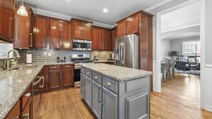 A modern kitchen with wooden cabinets, stainless steel appliances, and a granite countertop. - Luxury Home - ATL - No Cleaning Fee! (Austell)