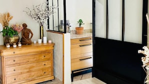 Une pièce comprenant une commode en bois, un banc, un miroir avec un cadre noir et un élément décoratif mural.