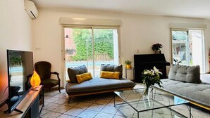 Un salon comprenant un canapé, des fauteuils, une table basse et un téléviseur.