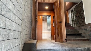 Un intérieur moderne avec un mur en pierre, un lambris en bois et un escalier menant à un ascenseur.