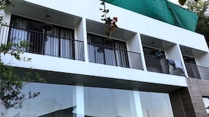 Un bâtiment moderne à deux étages, doté de balcons, de grandes fenêtres et d’une bâche verte recouvrant une partie du toit.