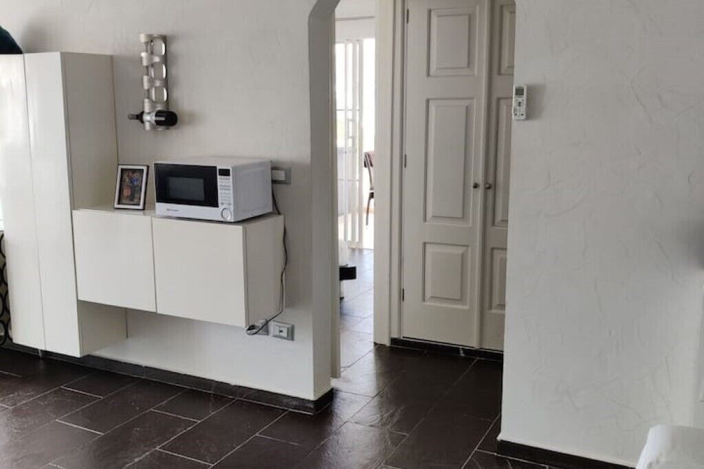 Eine Küche mit einer Mikrowelle auf einem weißen Schrank, einer Steckdose und einer Tür zu einem anderen Raum.
