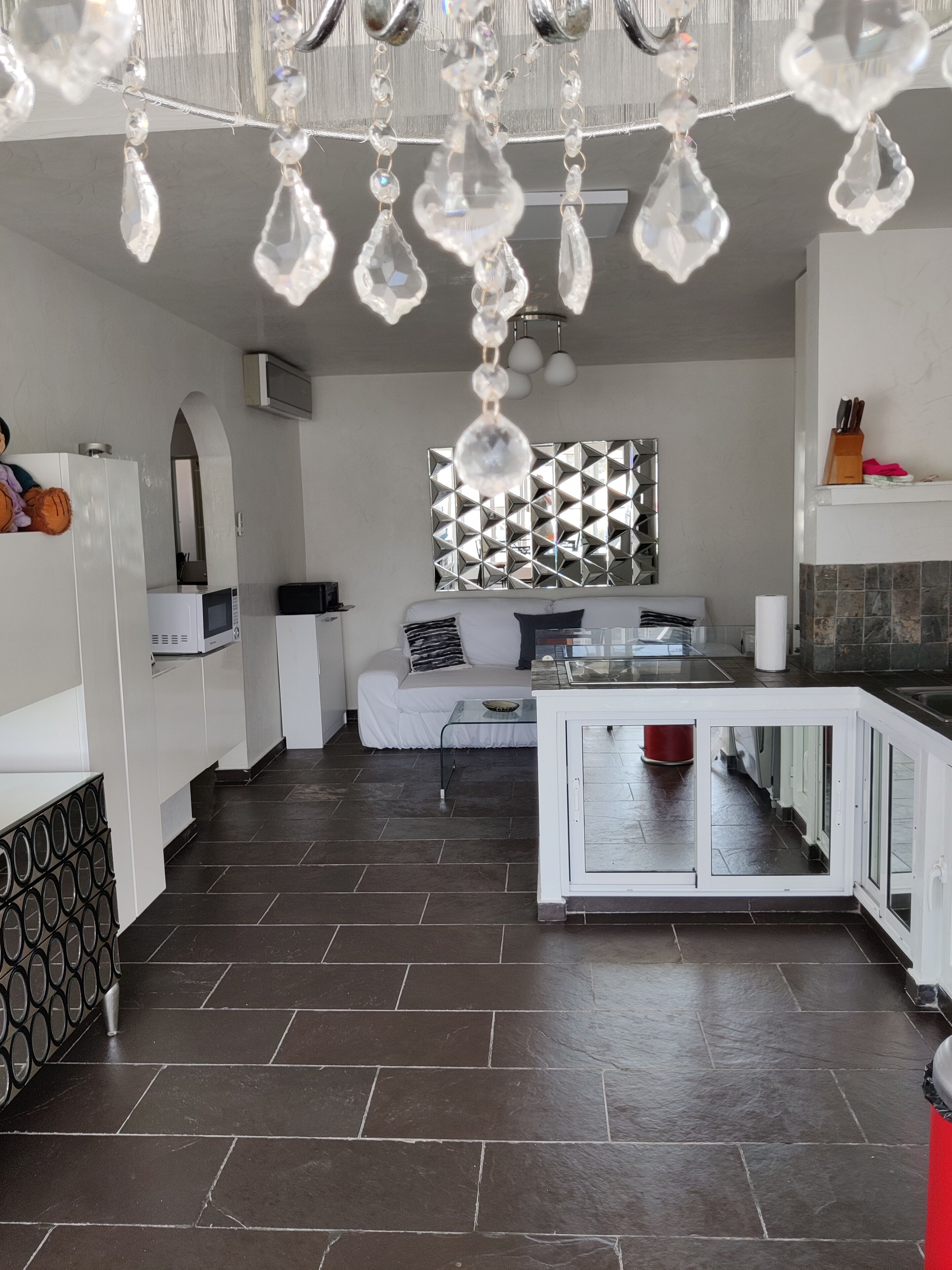 Une cuisine moderne avec des meubles blancs, un îlot central et un lustre décoratif.