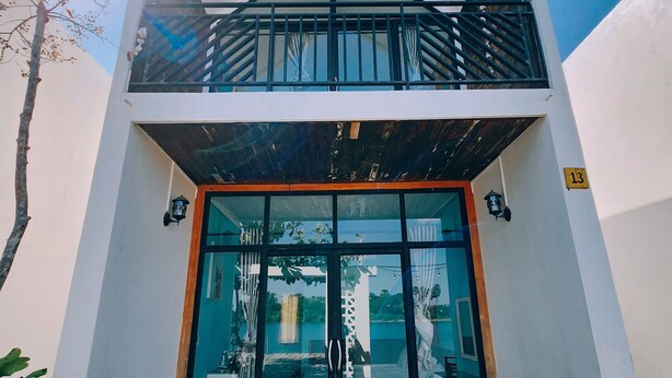 A modern two-story building with a balcony, large glass doors, and a number 13 sign. - Port Ville Resort (Kampot)