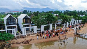 A beachfront property with modern architecture, including a large pool area and a gathering space with a view of the mountains. - Port Ville Resort (Kampot)