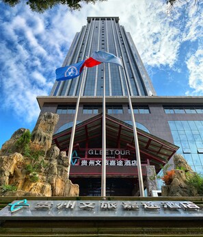 A tall building with a modern glass facade and a red entrance.