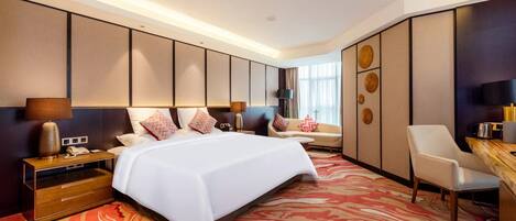 A modern hotel room with a large bed, a sofa, a desk, and a chair.