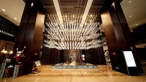 A spacious lobby with a large chandelier, wooden paneling, and a reception desk. - Gleetour Hotel Guizhou  (Qiandongnan)