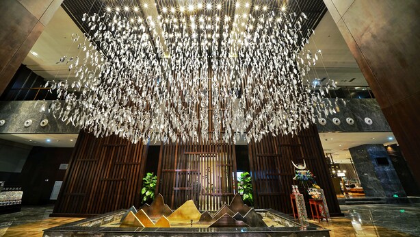 A modern lobby with a unique chandelier, a reception desk, and a water feature. - Gleetour Hotel Guizhou  (Qiandongnan)