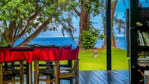 A wooden deck with a table and chairs, overlooking a beach with a view of the ocean. - Teahupoo: beachfront, the lagoon and the wave, at the foot of the mountains ! (teahupoo)
