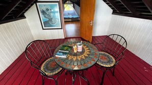 A small, enclosed patio area with a round table and two chairs, a wooden door, and a framed picture on the wall. - Teahupoo: beachfront, the lagoon and the wave, at the foot of the mountains ! (teahupoo)