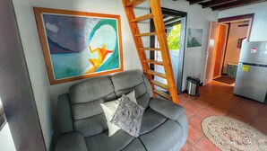 A living room with a gray sofa, a wooden ladder, a framed painting, and a refrigerator. - Teahupoo: beachfront, the lagoon and the wave, at the foot of the mountains ! (teahupoo)