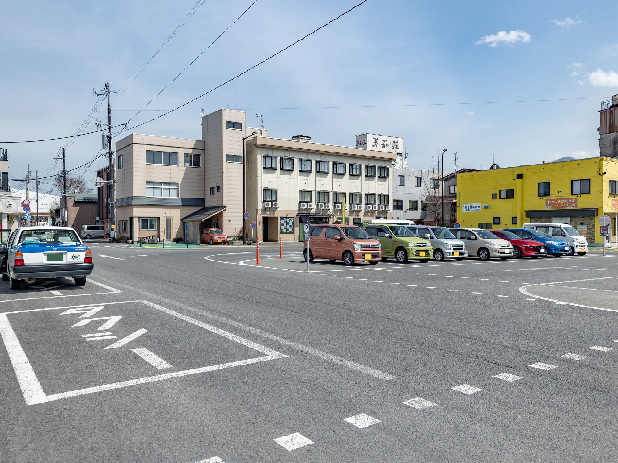 A street with parked cars and buildings, including a yellow building with a sign.
