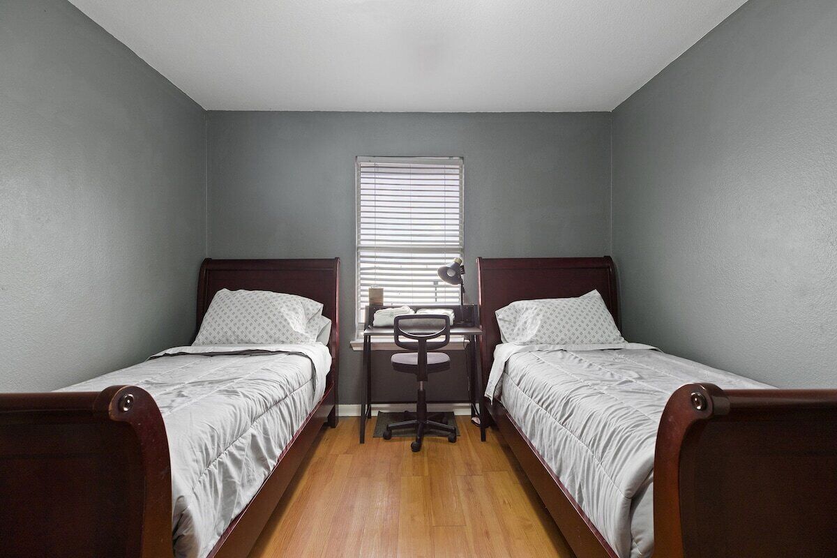 Un petit logement composé d’une seule pièce, comprenant deux lits simples, un bureau et une chaise.