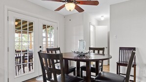 Un coin repas comprenant une table ronde, quatre chaises, un ventilateur de plafond et un vase en verre servant de centre de table.