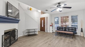 Un salon moderne avec une cheminée, un canapé en cuir noir, un banc et un ventilateur de plafond.