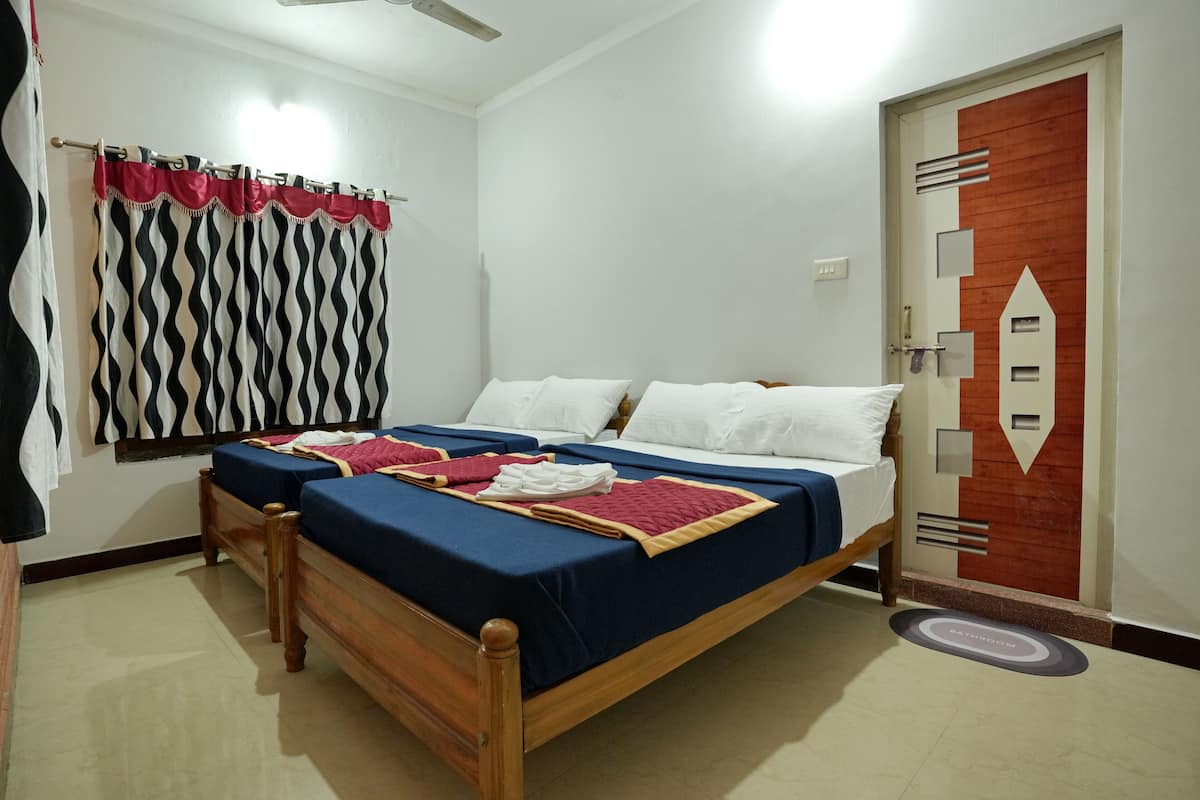 Une chambre avec deux lits simples, une tête de lit en bois, une fenêtre ornée d’un rideau à motifs et une porte au motif géométrique.