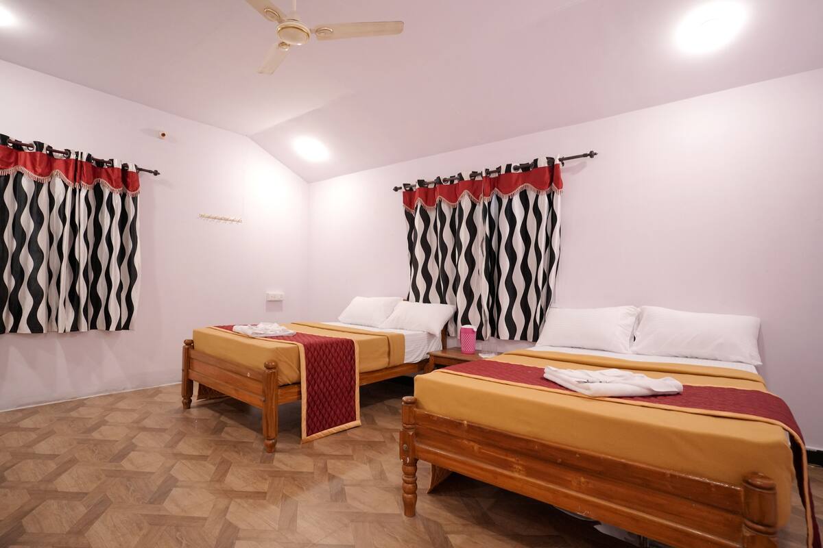 Une chambre d’hôtel avec deux lits en bois, un ventilateur de plafond et un plancher en parquet.