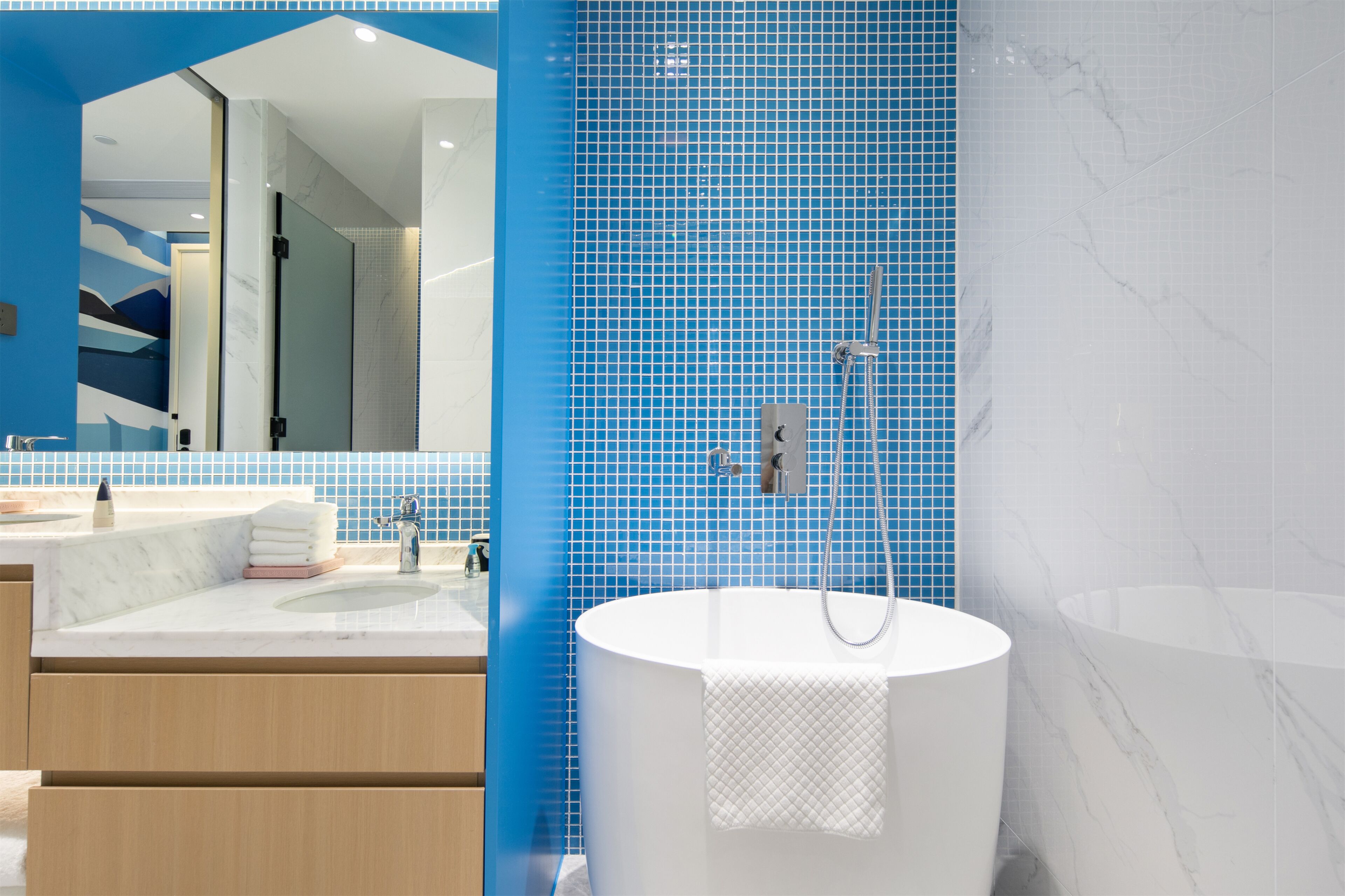 Un baño moderno con una bañera grande, un lavamanos con espejo y paredes con azulejos azules.