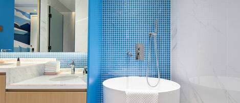 Un baño moderno con una bañera grande, un lavamanos con espejo y paredes con azulejos azules.