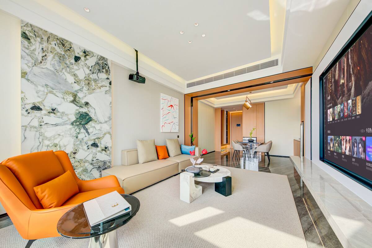 Uma sala de estar moderna com um sofá, poltrona laranja e uma mesa de centro.