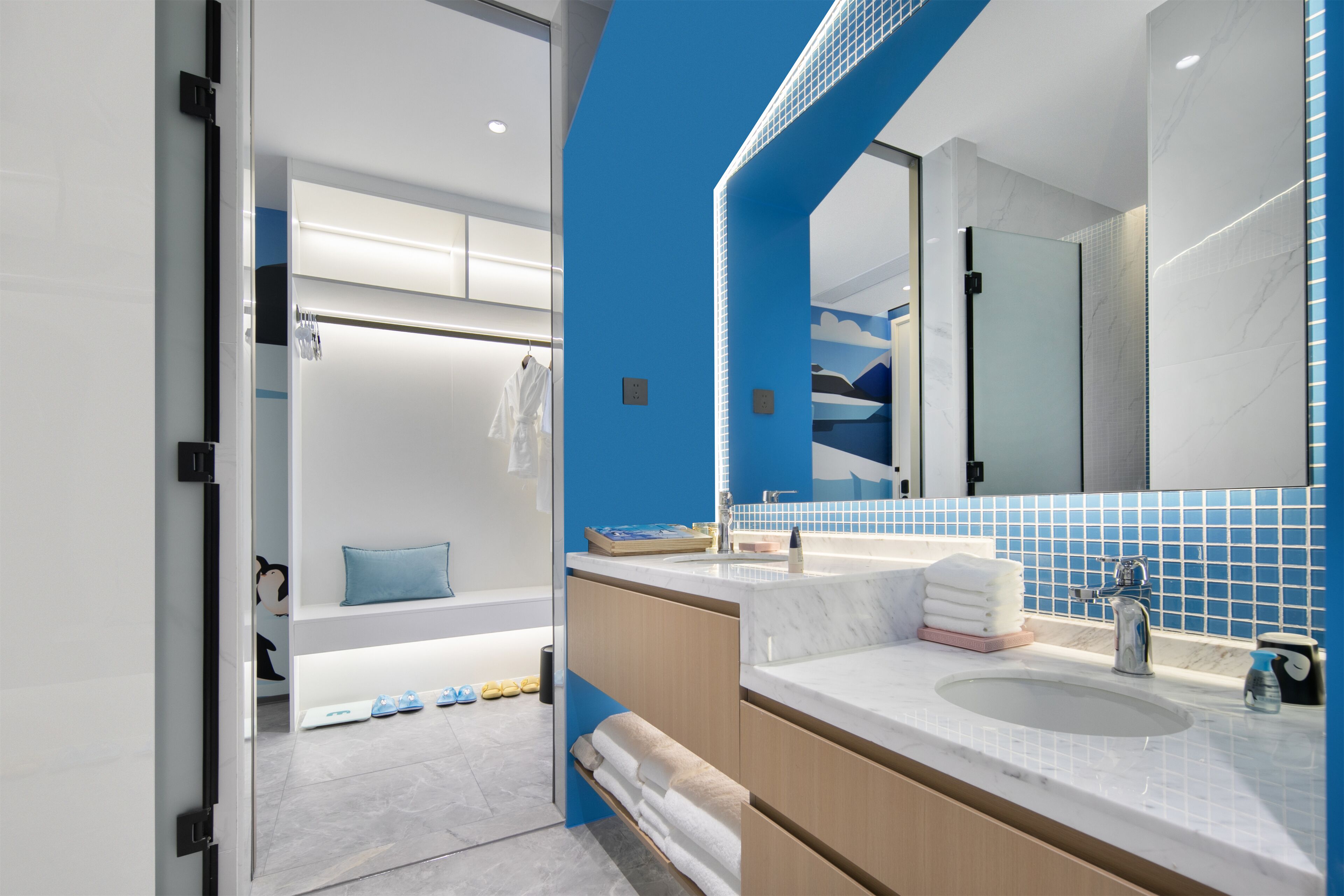 A modern bathroom with a large mirror, two sinks, and a blue accent wall.