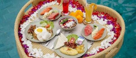 A floating dining setup on a pool with various dishes and drinks.