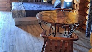A log cabin interior with a wooden dining table and chairs, a sofa, and a painting on the wall. - GOLDEN FISH GROUP (Urtasaray)