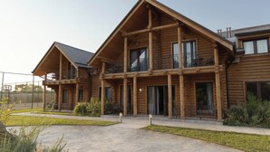 A two-story log cabin with a balcony on the upper floor, a covered porch, and a fenced outdoor area. - GOLDEN FISH GROUP (Urtasaray)